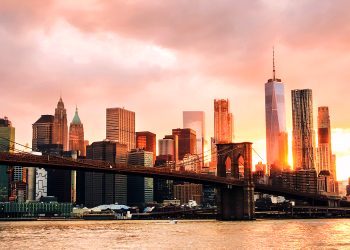 New York, USA. View of Manhattan bridge and Manhattan in New York, USA at sunset. Colorful cloudy sky with skyscrapers. Sun setting behind the skyscrapers