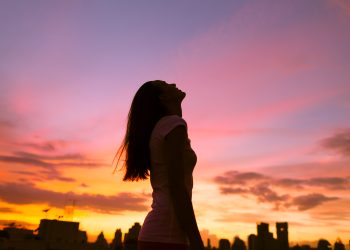 Happy,Woman,In,The,City,Looking,Up,Into,The,Sky.