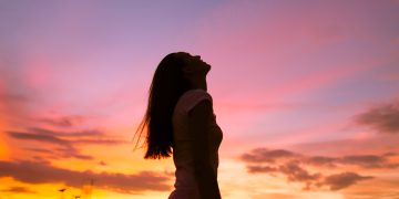 Happy,Woman,In,The,City,Looking,Up,Into,The,Sky.