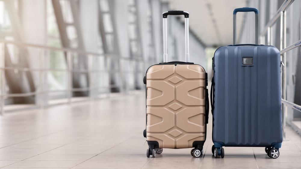 Two,Stylish,Suitcases,Standing,In,Empty,Airport,Hall,,Unrecognizable,Traveller's